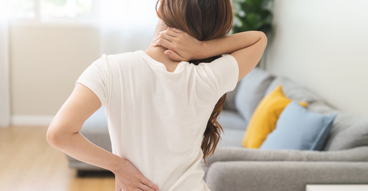 donna si mette una mano sulla schiena dolorante