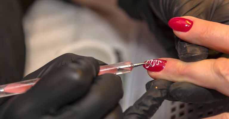 Nail artist decora le unghie di una cliente 