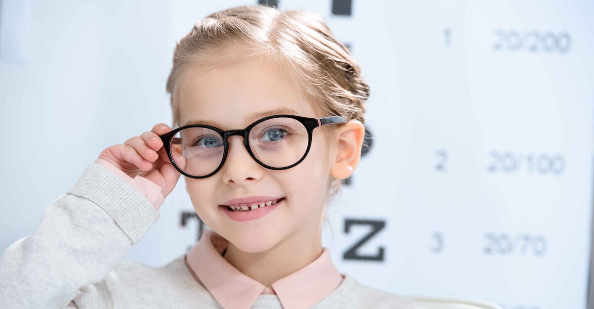 Bambina con occhiali da vista che sorride all'interno di un ottico
