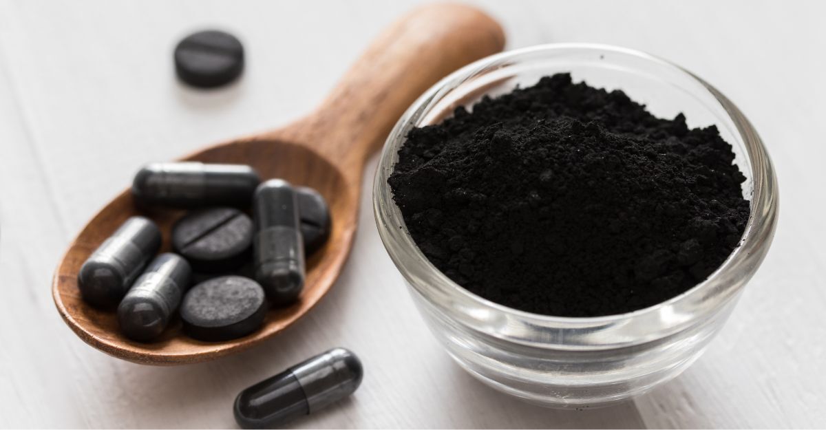 Carbone vegetale nero in una ciotola e sotto forma di compresse