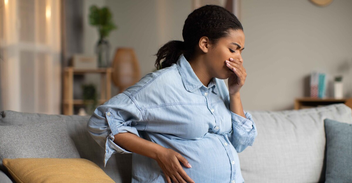 Donna in gravidanza si porta una mano alla bocca ed è sofferente