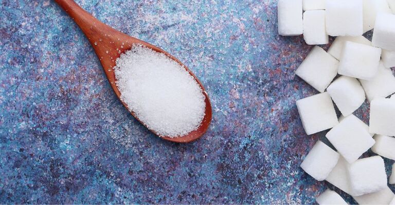 Cucchiaio di zucchero con zollette al lato