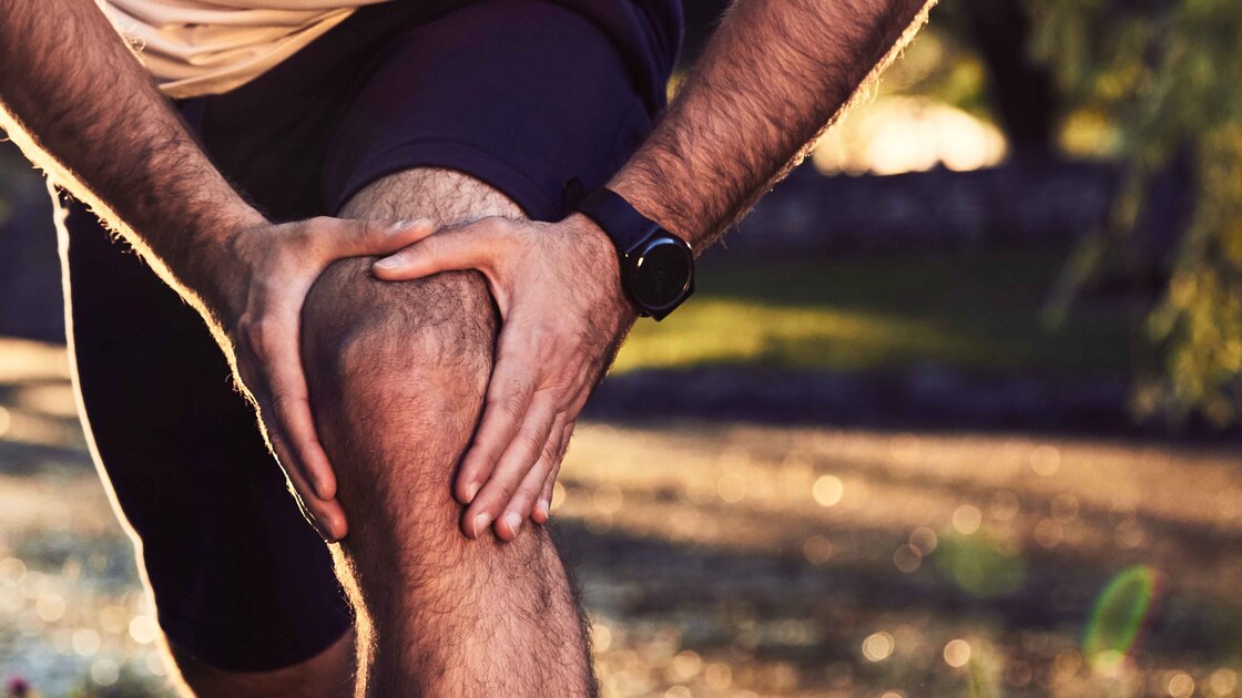 Uomo si tiene il ginocchio dolorante