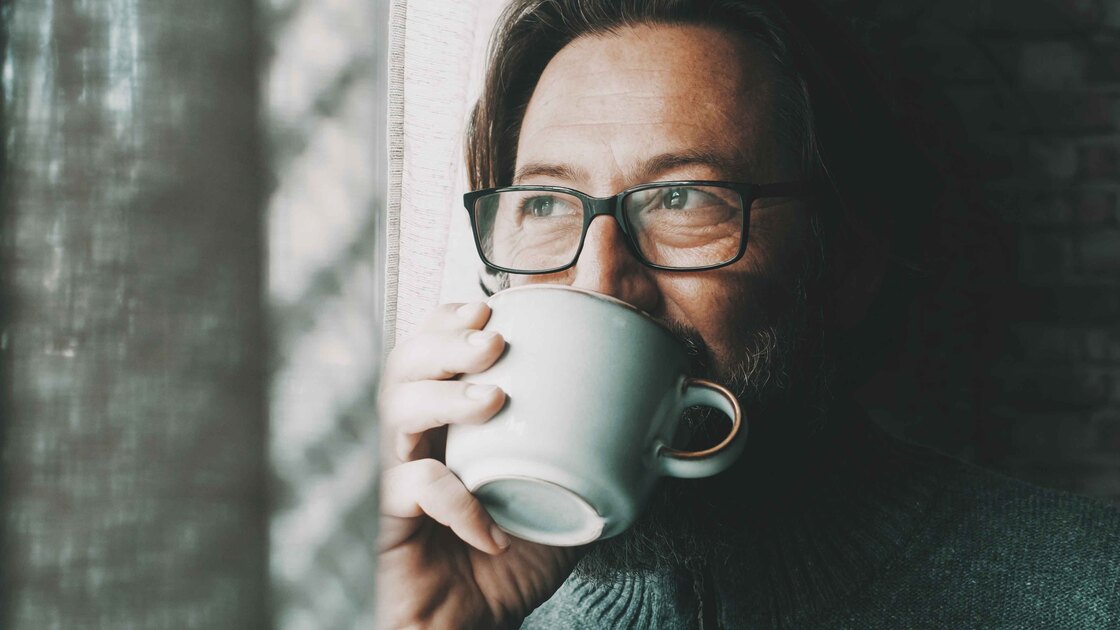 Un uomo beve una tisana alla finestra