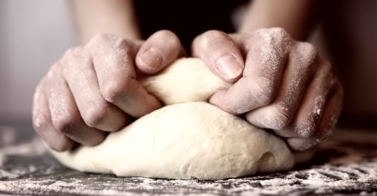 Una persona che sta lavorando l'impasto della pizza