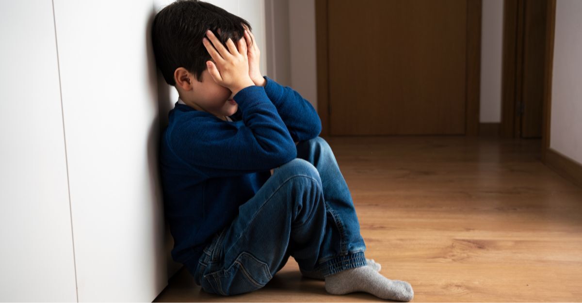 Bambino agitato seduto con mani sul viso