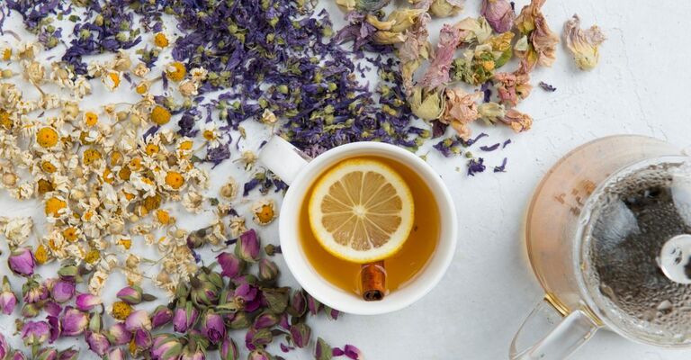 Tazza con infuso e introno erbe e fiori e una teiera