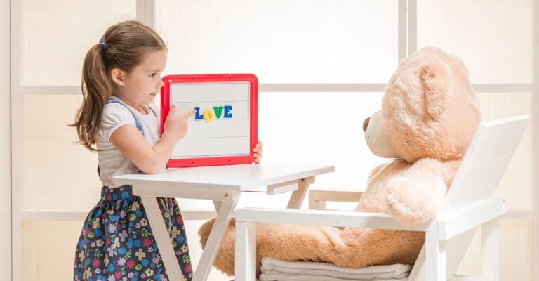 bimba gioca con orso di peluches