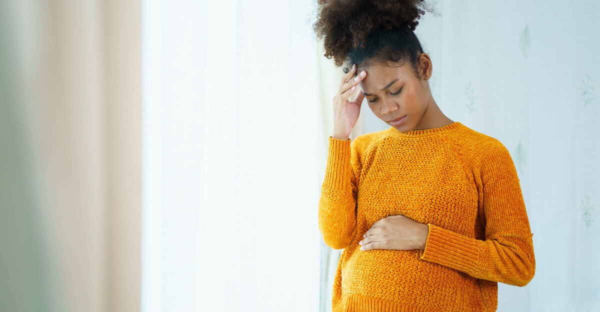 Una donna in gravidanza si tiene la testa