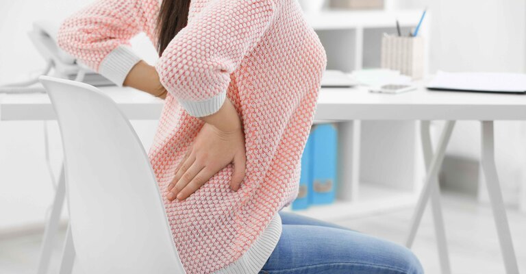 Una ragazza seduta con il mal di schiena