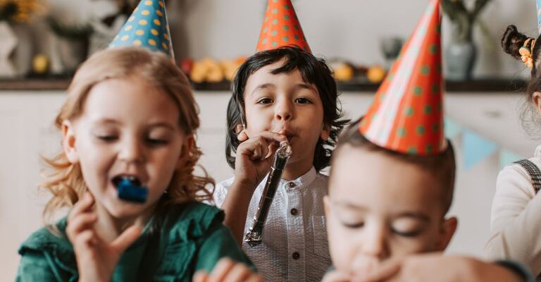 Bambini che festeggiano un compleanno con festoni e cappellini