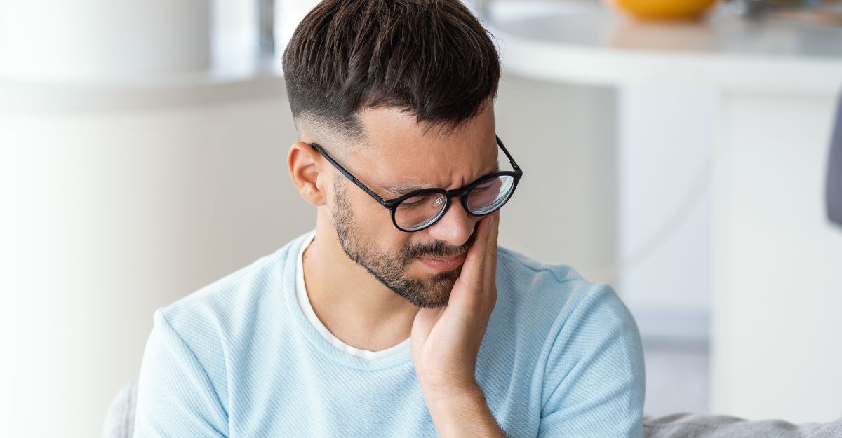 Un ragazzo si tiene la guancia dolorante