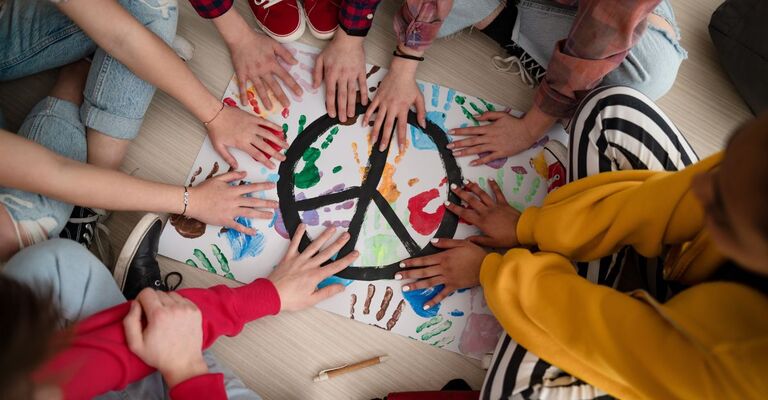 mani di bambini sopra il disegno del simbolo della pace