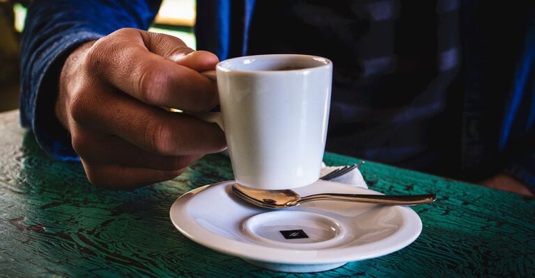 Mano di uomo tiene in mano una tazzina di caffè
