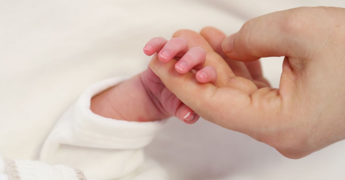 La mano di una madre che prende quella del neonato