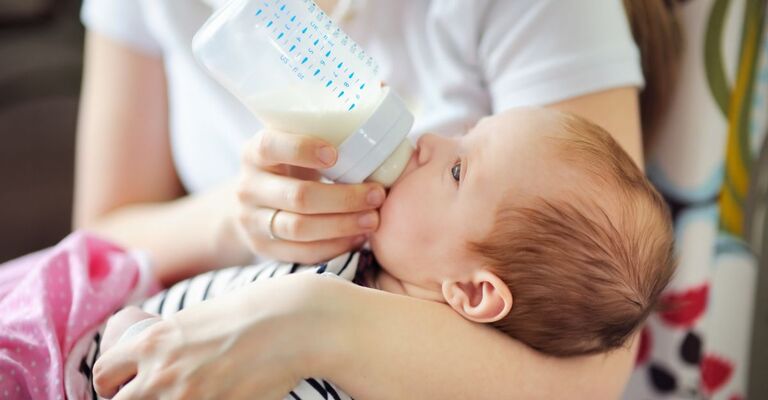 Un neonato beve del latte dal biberon