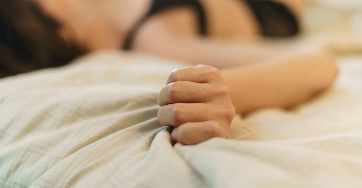 Donna stringe il lenzuolo sdraiata sul letto