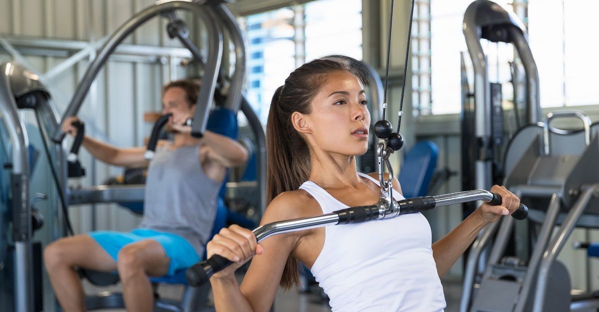 Due persone in palestra, uomo e donna, utilizzano la lat machine in palestra