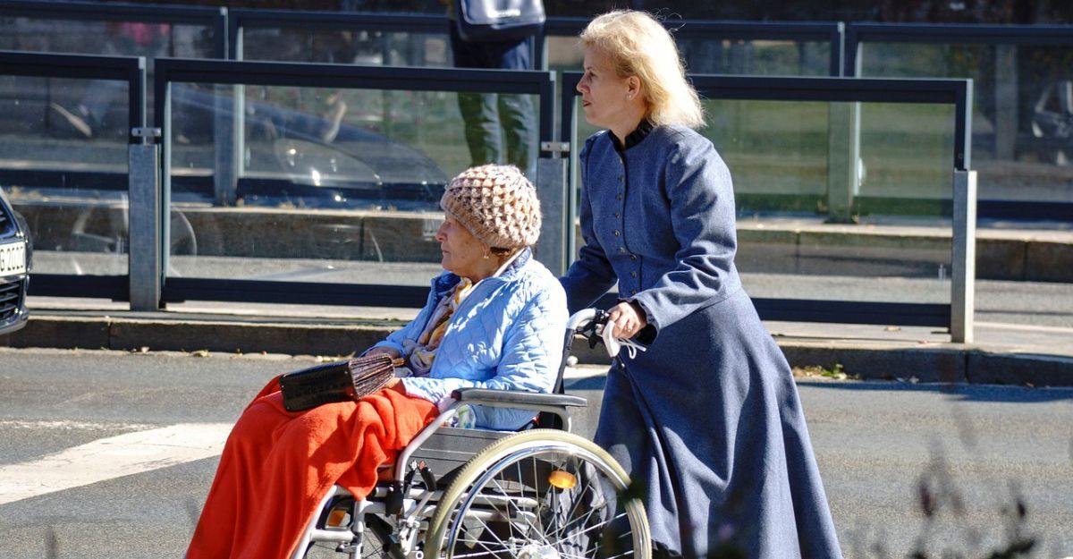 donna-caregiver-che-spinge-anziana-in-carrozzina