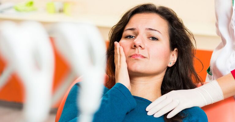 Ragazza dolorante seduta sulla poltrona del dentista