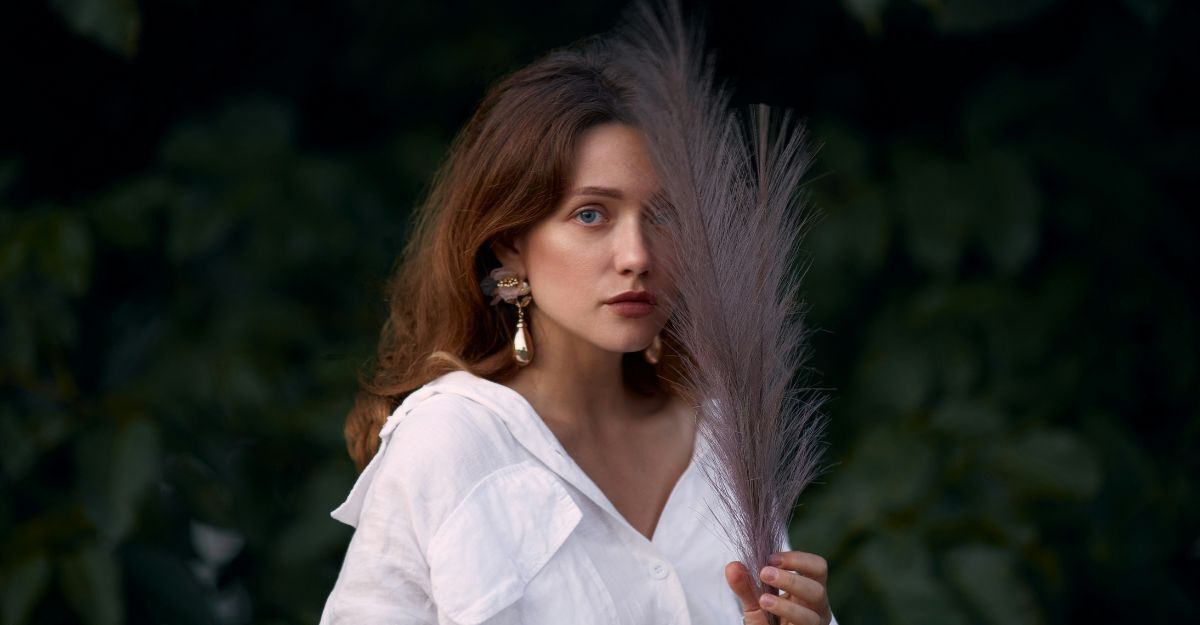 Ragazza posa con una piuma posata sul volto