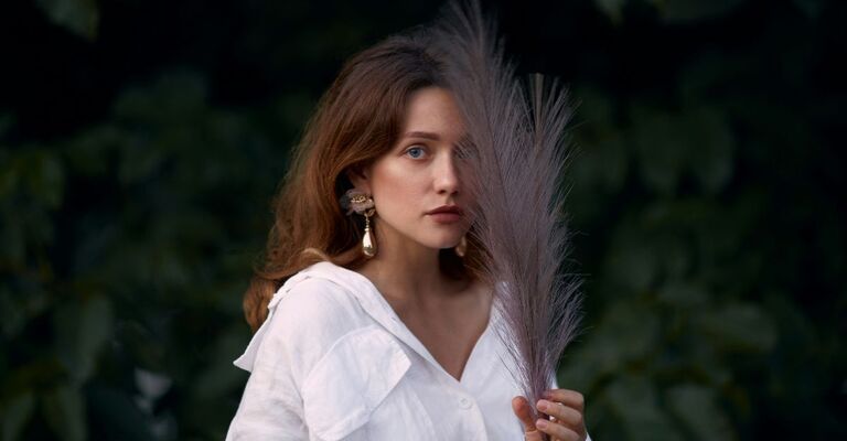 Ragazza posa con una piuma posata sul volto