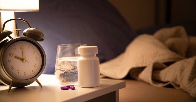 Pastiglie e acqua sul comodino vicino al letto