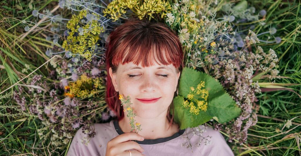 Ragazza sdraiata su un prato sorride felice