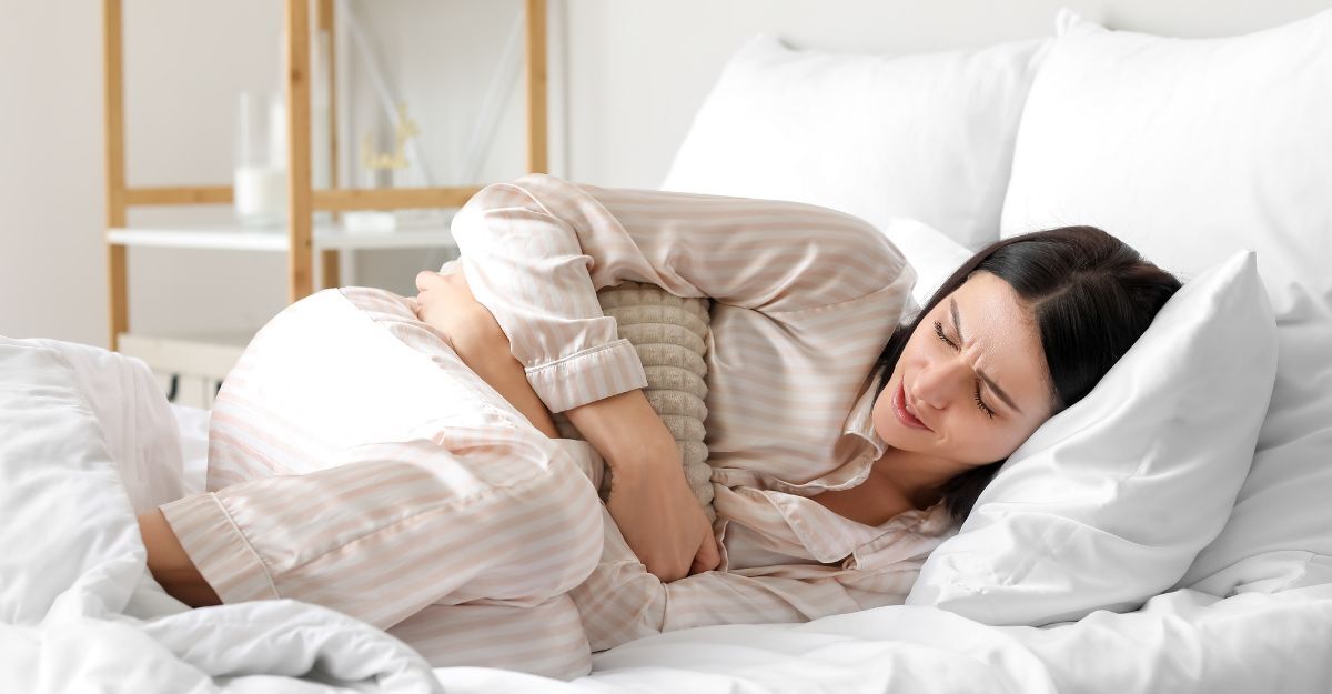 Ragazza rannicchiata su un letto con i dolori mestruali