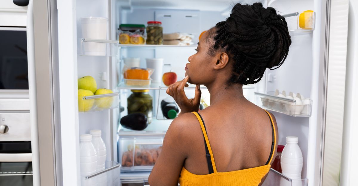 Ragazza con porta del frigo aperta si chiede cosa mangiare