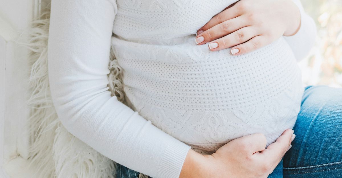 Donna incinta seduta con pancia in primo piano