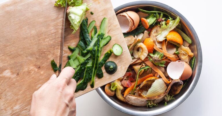 Scarti di verdure presi dal un tagliere e raccolti in una ciotola
