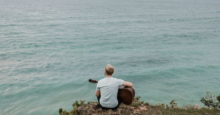 Un ragazzo con una chitarra sul mare