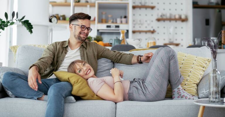 Coppia sul divano che ride con complicità