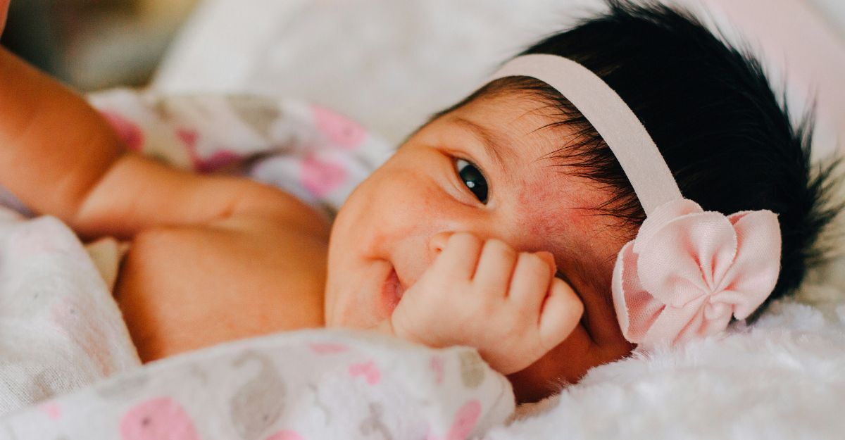 Neonata vestita con una coroncina sorride da sdraiata