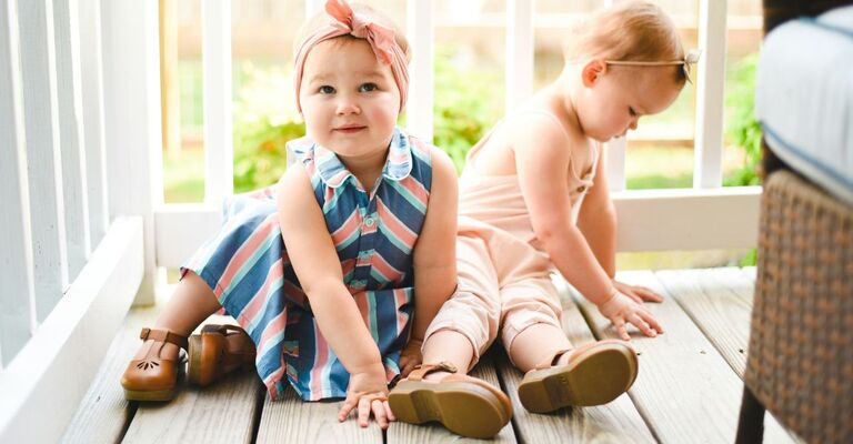 Due bambine per terra che sorridono e si guardano in giro