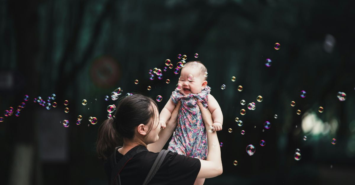Bambina viene sollevata dalla mamma in mezzo alle bolle di sapone