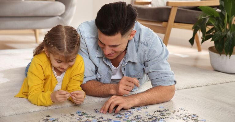 Una bambina fa un puzzle con il papà