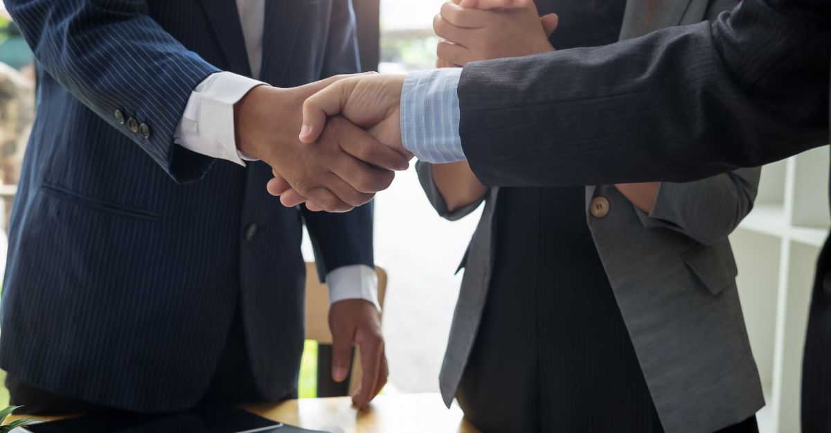 Un uomo in giacca e cravatta stringe la mano ad un altro uomo