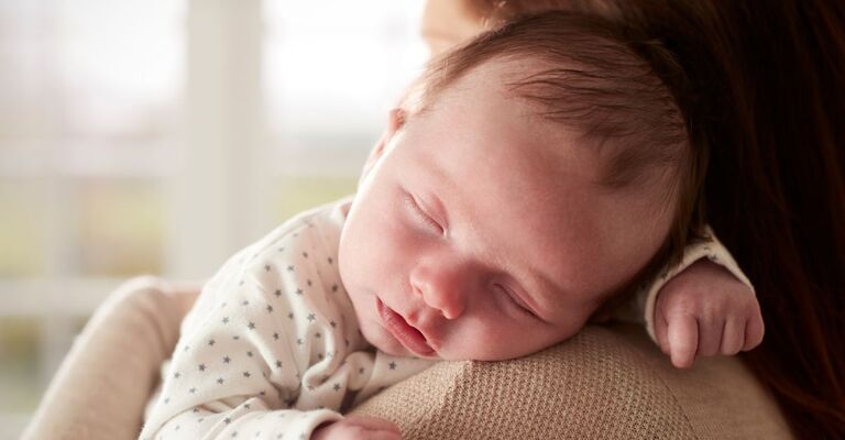 Neonato appoggiato sulla spalla della mamma