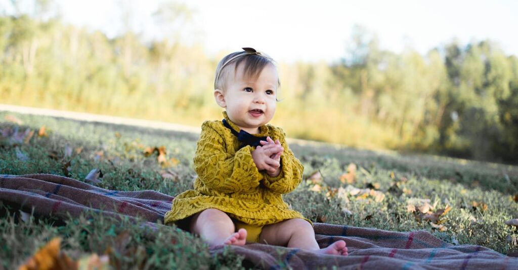 Neonata in un prato che sorride