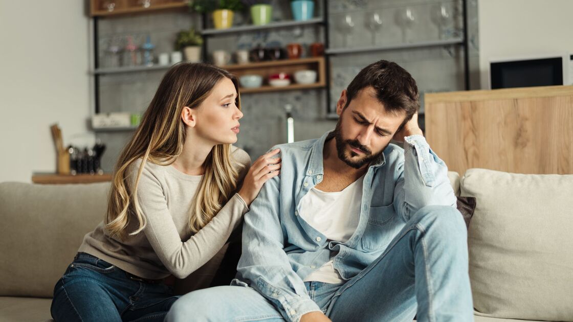 Ragazza rassicura fidanzato mentre sono seduti sul divano