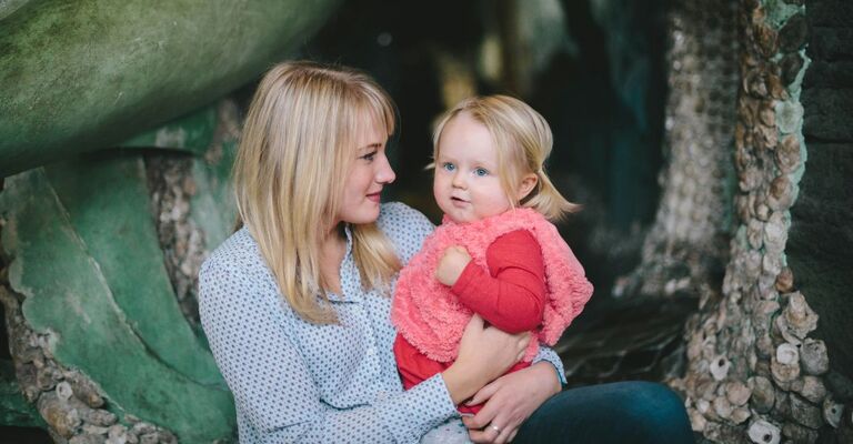 Giovane mamma tiene in braccio la figlia nella natura