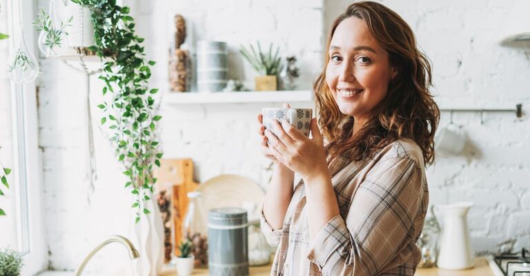 Ragazza che beve da una tazza in cucina