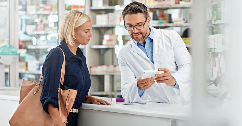 Cliente al bancone parla col farmacista dell'acquisto di un farmaco