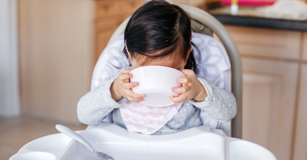 bimba beve il brodo sul seggiolone