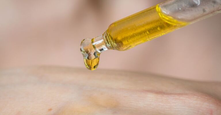 Una persona si mette una goccia di olio sulla mano