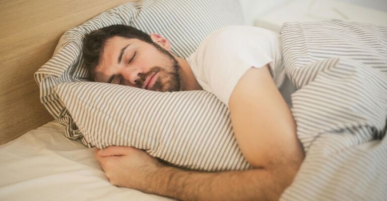 Uomo che dorme col cuscino abbracciato