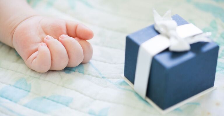 Mano di neonato con accanto una scatolina regalo