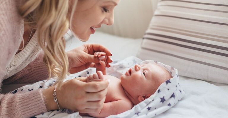 Mamma che interagisce con neonato sdraiato